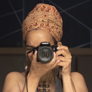 black woman in head wrap pointing her camera at camera