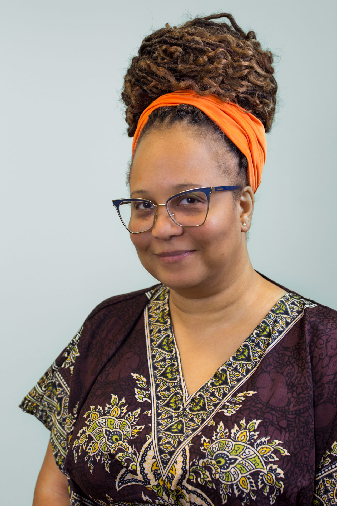 A headshot of Qiona Woffard against a neutral grey background.