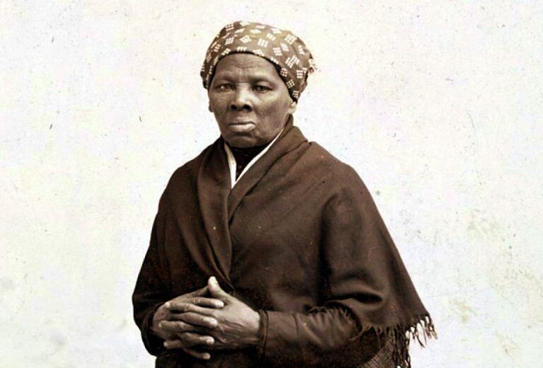 Black & white photo of Harriet Tubman wearing a dark wrap and a printed headscarf