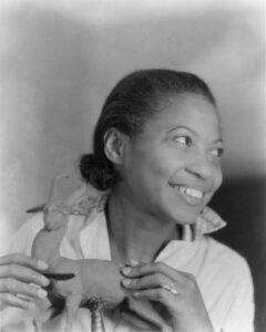 black woman in a white shirt is artist augusta savage holding one of her sculptures