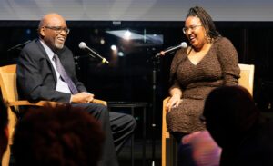 man and woman seated before audience laughing