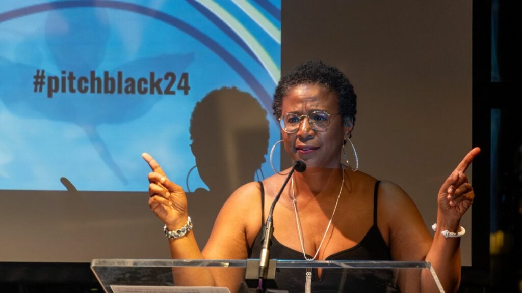 bpm president speaking and gesturing from a podium in a black cocktail dress